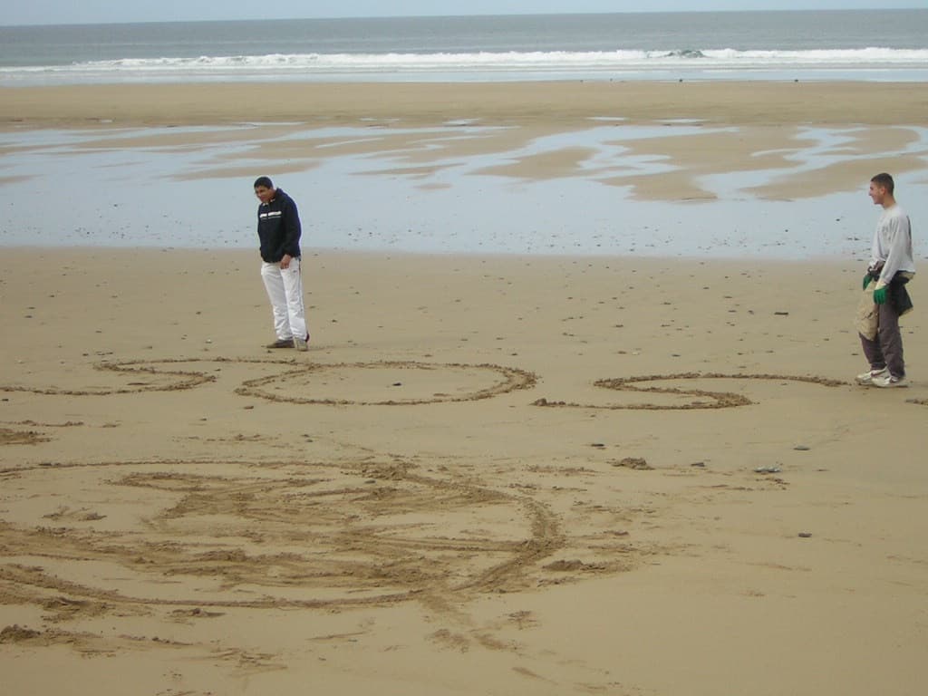 Message dessiné dans le sable à marée basse, deux jeunes à côté