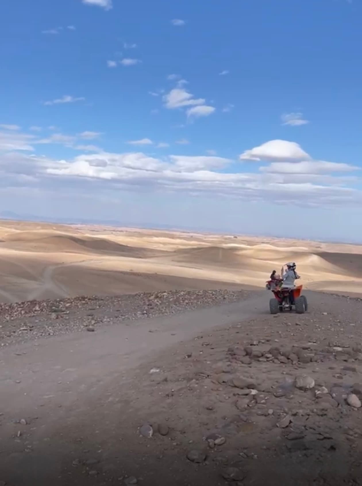 Quad sur une piste du désert marocain, face aux dunes